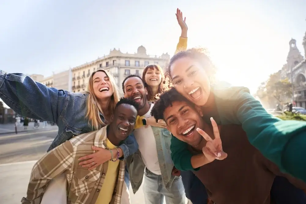 En gruppe studerende tager et selfie i en europæisk by under en studietur.